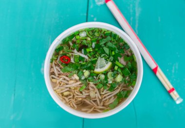 Turkuaz ahşap masada Pho Bo çorbası. Tek kullanımlık plastik tabakta çorba. Asya yemekleri.