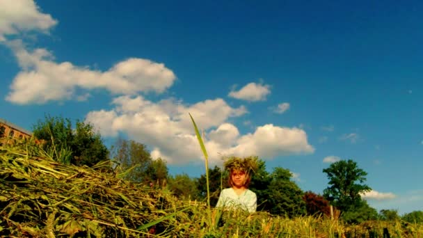 Sarışın kızı bir çiftçinin saman yapılan bir çelenk örgüleri — Stok video
