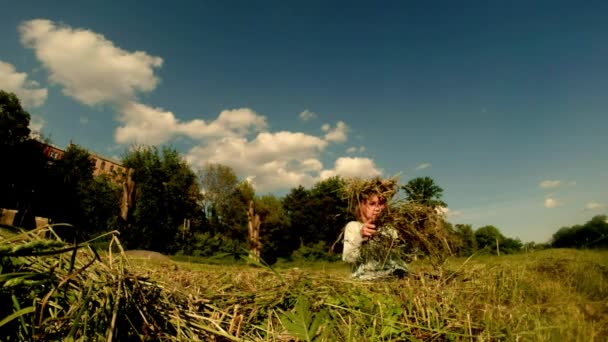 Fair-haired daughter of a farmer weaves a wreath made of straw — Stock Video