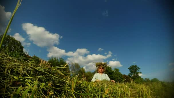 Fair-haired daughter of a farmer weaves a wreath made of straw — Stock Video