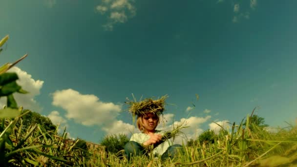 Figlia di un contadino dai capelli biondi tesse una corona di paglia — Video Stock