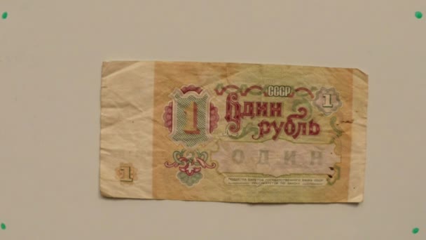 Papier monnaie un rouble URSS en 1991 sur une table blanche retourné une main de près 
