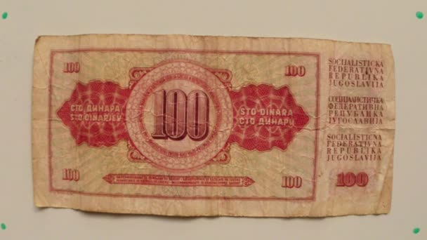 Papierowe pieniądze 100 dinarów Banku Narodowego Jugosławii w 1986 na stół biały odwrócenie rękę z bliska — Wideo stockowe