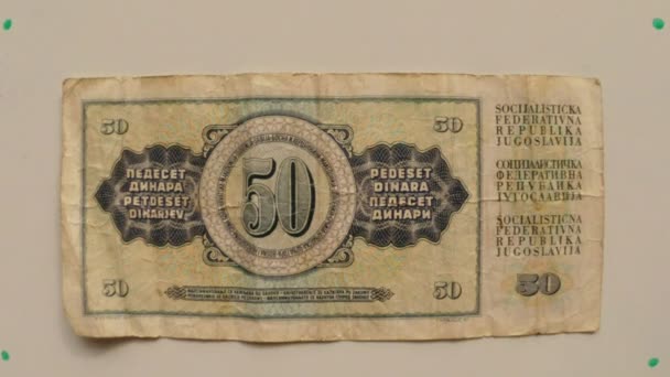 Papier monnaie 50 dinars Yougoslavie en 1976 sur une table blanche retourné une main de près 