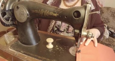 Büyükanne Sovyetler Birliği retro bir eski dikiş makinesinde bir kırmızı bayrak diker, tüm koleksiyon - birçok süper yakın çekimler, renk düzeltme için Raw formatta görmek