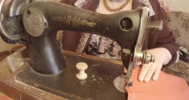 Büyükanne Sovyetler Birliği retro bir eski dikiş makinesinde bir kırmızı bayrak diker, tüm koleksiyon - birçok süper yakın çekimler, renk düzeltme için Raw formatta görmek