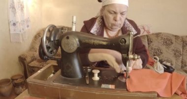 Büyükanne Sovyetler Birliği retro bir eski dikiş makinesinde bir kırmızı bayrak diker, tüm koleksiyon - birçok süper yakın çekimler, renk düzeltme için Raw formatta görmek