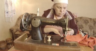 Büyükanne Sovyetler Birliği retro bir eski dikiş makinesinde bir kırmızı bayrak diker, tüm koleksiyon - birçok süper yakın çekimler, renk düzeltme için Raw formatta görmek