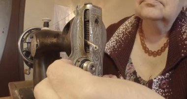 Büyükanne Sovyetler Birliği retro bir eski dikiş makinesinde bir kırmızı bayrak diker, tüm koleksiyon - birçok süper yakın çekimler, renk düzeltme için Raw formatta görmek