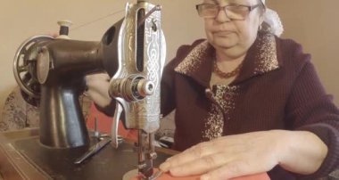 Büyükanne Sovyetler Birliği retro bir eski dikiş makinesinde bir kırmızı bayrak diker, tüm koleksiyon - birçok süper yakın çekimler, renk düzeltme için Raw formatta görmek