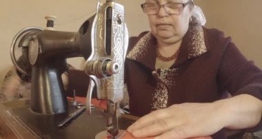 Büyükanne Sovyetler Birliği retro bir eski dikiş makinesinde bir kırmızı bayrak diker, tüm koleksiyon - birçok süper yakın çekimler, renk düzeltme için Raw formatta görmek