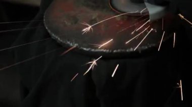 Sihirbaz bir metal davul sihirli sparks bir eski gaz çanta sonuçları yüzey parlatma üretimi için gaz çanta metal yüzey temizler çalışan karanlık bir garajda açı değirmeni grev kıvılcım
