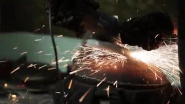 Sihirbaz bir metal davul sihirli sparks bir eski gaz çanta sonuçları yüzey parlatma üretimi için gaz çanta metal yüzey temizler çalışan karanlık bir garajda açı değirmeni grev kıvılcım