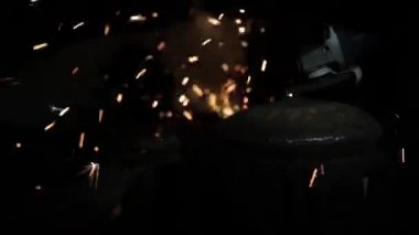 Sihirbaz bir metal davul sihirli sparks bir eski gaz çanta sonuçları yüzey parlatma üretimi için gaz çanta metal yüzey temizler çalışan karanlık bir garajda açı değirmeni grev kıvılcım