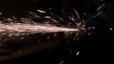 Sihirbaz bir metal davul sihirli sparks bir eski gaz çanta sonuçları yüzey parlatma üretimi için gaz çanta metal yüzey temizler çalışan karanlık bir garajda açı değirmeni grev kıvılcım