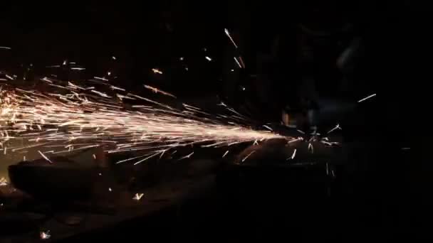 Winkelschleifer schlagen Funken in einer dunklen Garage läuft der Assistent für die Herstellung einer Metalltrommel magische Funken Polieren der Oberfläche eines alten Gasbeutels Ergebnisse reinigt die Metalloberfläche des Gasbeutels — Stockvideo