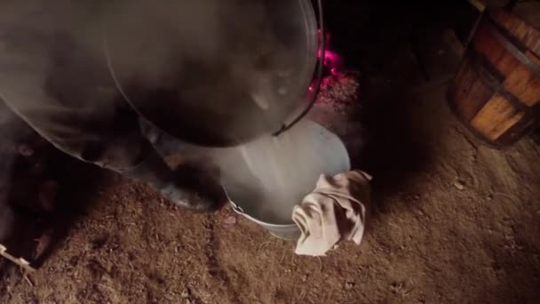 Ζεστό νερό χύνεται σε ένα κουβαδάκι στέκεται σε μια καλύβα των βοσκών στα βουνά — Αρχείο Βίντεο