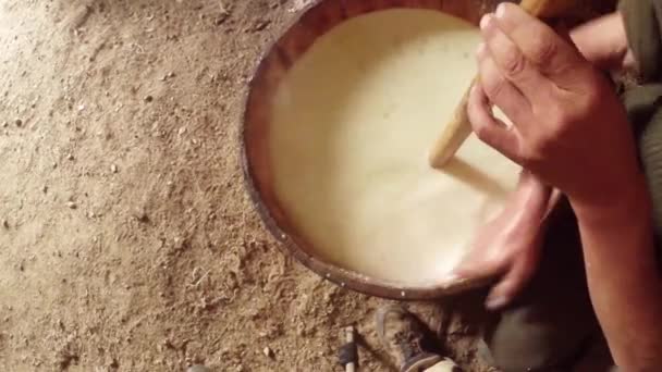 Manos del agricultor batido dispositivo de madera de leche en una enorme vista superior barril — Vídeos de Stock
