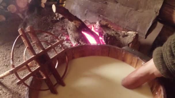 Barril de madeira com queijo quente, mãos de fazendeiro em leite, uma vista superior e um fogo na casa — Vídeo de Stock