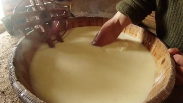 Hand in warm gegiste schapenmelk verzamelt grote brok van kaas in een houten emmer — Stockvideo