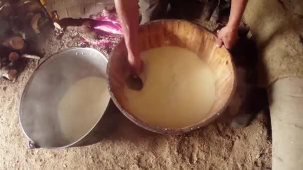 Mano en la leche de oveja fermentada caliente recoge gran masa de queso en un cubo de madera — Vídeos de Stock