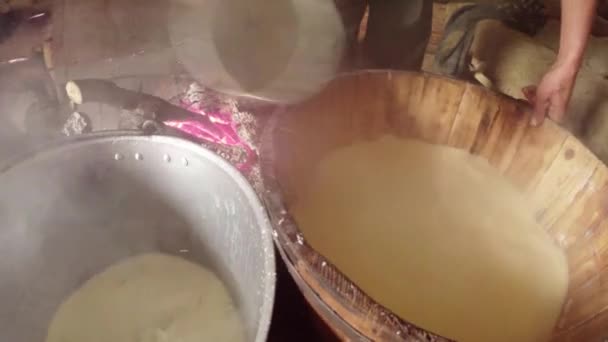 Hand van de landbouwer verzamelt cup vloeibare Wei van houten vaten met kaas — Stockvideo