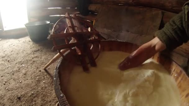 Mano en la leche de oveja fermentada caliente recoge gran masa de queso en un cubo de madera — Vídeos de Stock