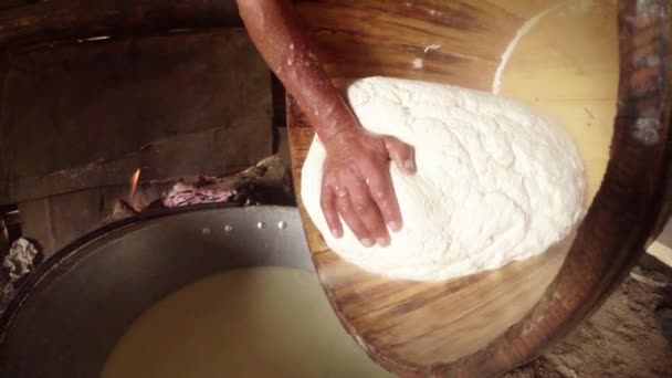 Large piece of feta cheese in a wooden tub decanted from residual liquid on the background of the barracks of the Shepherds — Stock Video