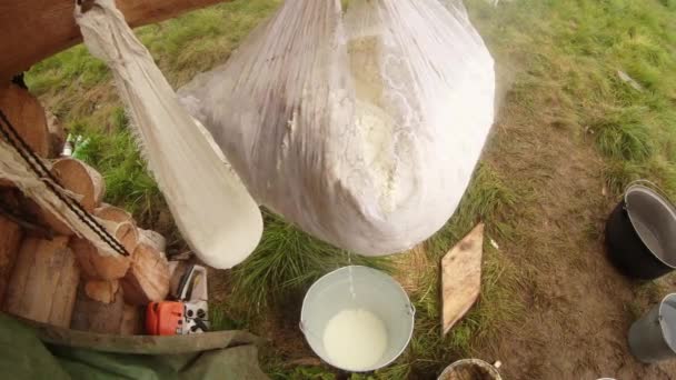 Grande pedaço de queijo fresco de ovelha envolto em uma gaze e pendurado para drenar o último do líquido no fundo da grama verde — Vídeo de Stock