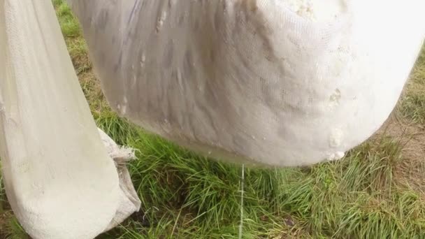 Gran pedazo de queso colgado en mantel de queso para la deshidratación, cerca de madera — Vídeos de Stock