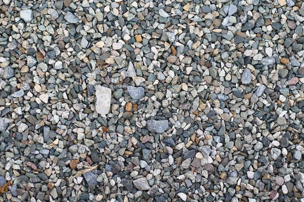 Small color stone texture for background. Color gravel stones for the construction industry. Top view of ground gravel road.