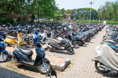 Motorbikes and scooters standing on a car parking space at the Madgoan railway station in Goa, India, transportation, march 9th 2025