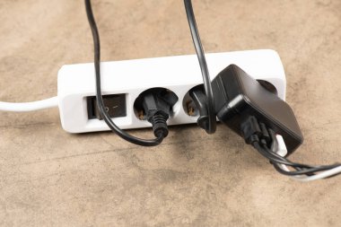 Extension power outlet socket overloaded with plugs, USB adapter with charge cables plugged into power strip