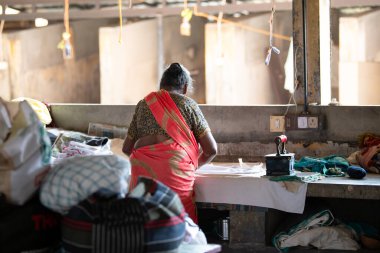 Geleneksel giysili kadın elinde antika bir kömür ütüsüyle, Dhobi Ghat, Kochi, Hindistan 'da 29 Mart 2025' te hava çamaşırhanesini açıyor.