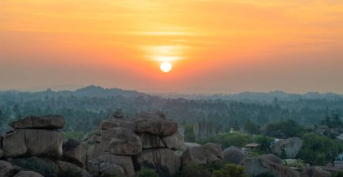 Hemakuta Hill 'den Hampi, gün batımı manzaralı, palmiye ağaçlı kaya manzaralı, Hindistan' da Karnataka, seyahat yeri.