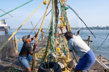 Kochi sahilindeki Çin balıkçı ağları, Hindistan 'daki Kerala, Cheenavala veya Tangkul' da balıkçılar 20 Mart 2025 'te geleneksel sabit kaldırma ağının taşlarını kaldırdılar.