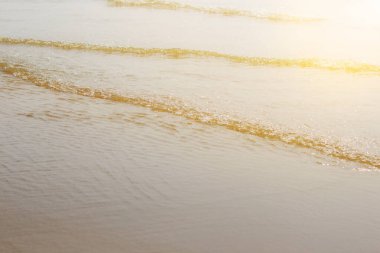 Sahilde güneş ışığıyla birlikte su dalgaları.