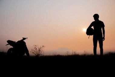 Motosikletli adamlar gün batımında gökyüzünde.