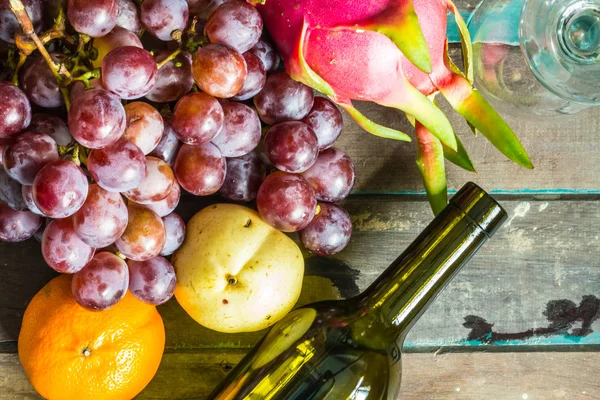 Viele Früchte und Weinflaschen — Stockfoto