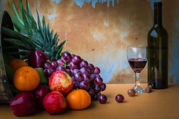 Frutta e bottiglie di vino su legno Immagine Stock