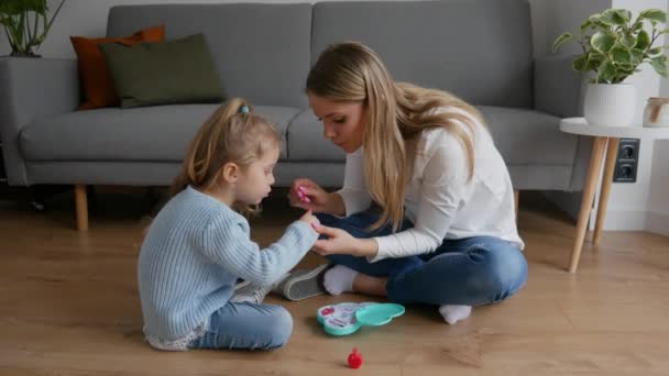 母と娘はおもちゃのネイルポリッシュで爪をペイントします 子供は家でママと遊ぶ 良い子育てと幸せな子供時代 家族のレジャーの概念 — ストック動画