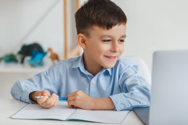 Akıllı çocuk dizüstü bilgisayar ve internet kullanarak ev ödevi yapıyor. İlköğretim okulunu video aracılığıyla öğreniyorum. Çocuk evde online çalışıyor.