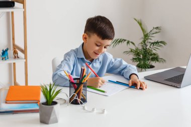 Akıllı çocuk dizüstü bilgisayar ve internet kullanarak ev ödevi yapıyor. İlköğretim okulunu video aracılığıyla öğreniyorum. Çocuk evde online çalışıyor.