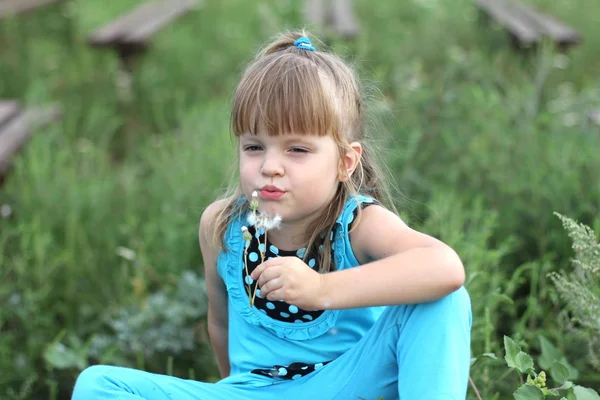 Маленькая девочка с длинными волосами играет на траве летом — стоковое фото