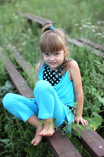 Liten flicka med långt hår spela på gräs på sommaren — Stockfoto