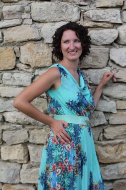 bir mavi uzun siyah kıvırcık kısa saçlı gülümseyen genç bir kadın portresi elbise