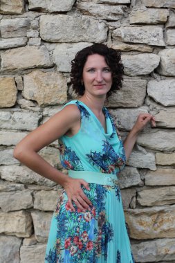 bir mavi uzun siyah kıvırcık kısa saçlı gülümseyen genç bir kadın portresi elbise