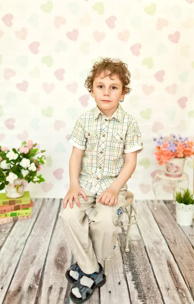 Porträt eines lockigen Jungen mit braunen Augen in einem hellbeigen Kleid — Stockfoto