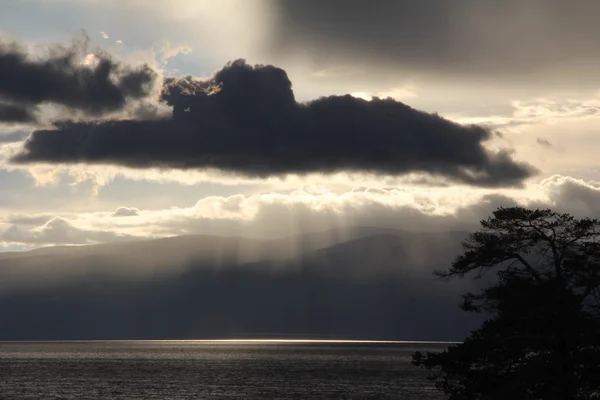 バイカル湖の自然、オルコン島、ロシア、夕暮れ時の湖の上に灰色の雲、バイカル湖の美しい自然、湖、川に雲とオレンジ黄色の空と美しい夕日 — ストック写真