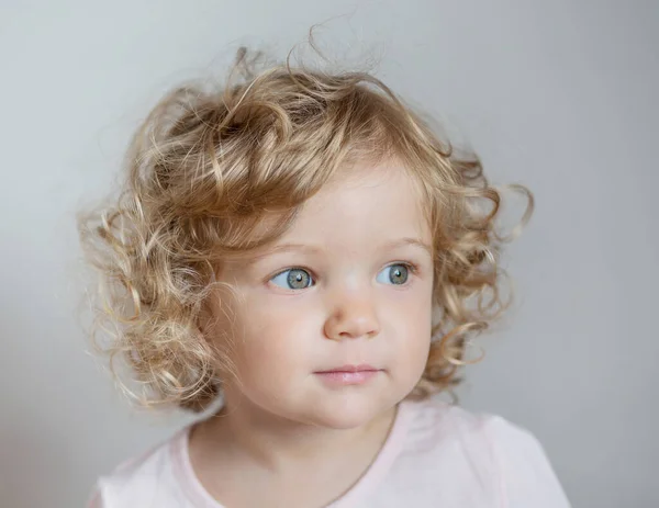 Curly beautiful European baby girl on light gray background — Stock Photo, Image